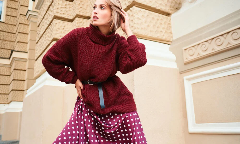 Μοντέρνα γυναίκα φορώντας μίνι φούστα με πλεκτό πουλόβερ σε αστικό περιβάλλον.