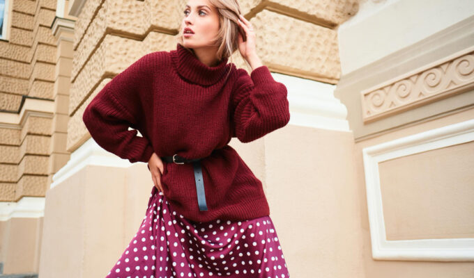 Μοντέρνα γυναίκα φορώντας μίνι φούστα με πλεκτό πουλόβερ σε αστικό περιβάλλον.