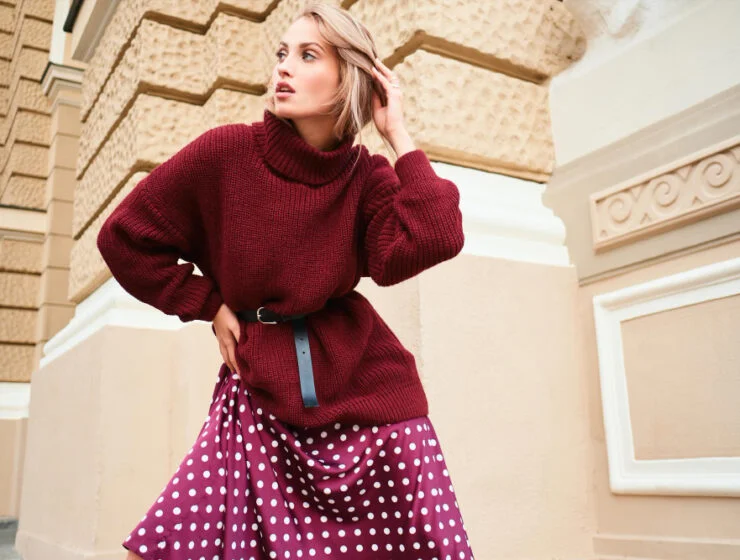 Μοντέρνα γυναίκα φορώντας μίνι φούστα με πλεκτό πουλόβερ σε αστικό περιβάλλον.